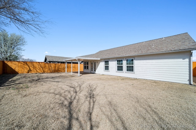 rear view of property featuring a patio, a shingled roof, french doors, and a fenced backyard