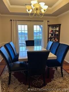 dining space featuring a raised ceiling, a notable chandelier, and crown molding