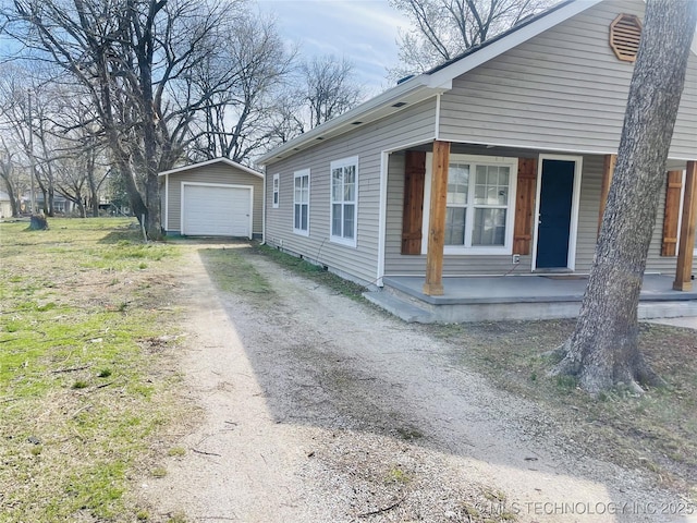 view of property exterior featuring an outbuilding, driveway, a porch, and a garage