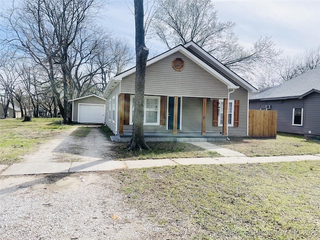 bungalow-style home featuring a detached garage, dirt driveway, covered porch, an outdoor structure, and a front yard