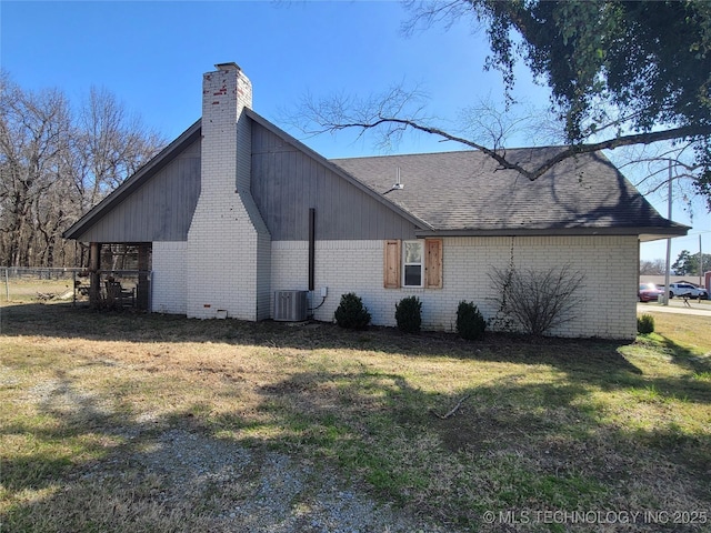 view of property exterior featuring roof with shingles, a yard, a chimney, central air condition unit, and brick siding