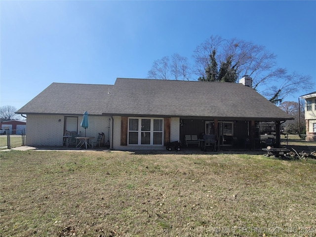 rear view of property featuring a yard, brick siding, and a chimney