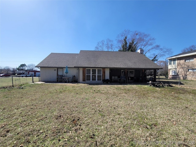 back of property featuring brick siding, a lawn, a chimney, and fence