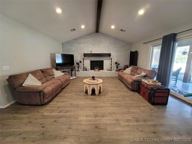 living room featuring visible vents, a fireplace, wood finished floors, and vaulted ceiling with beams