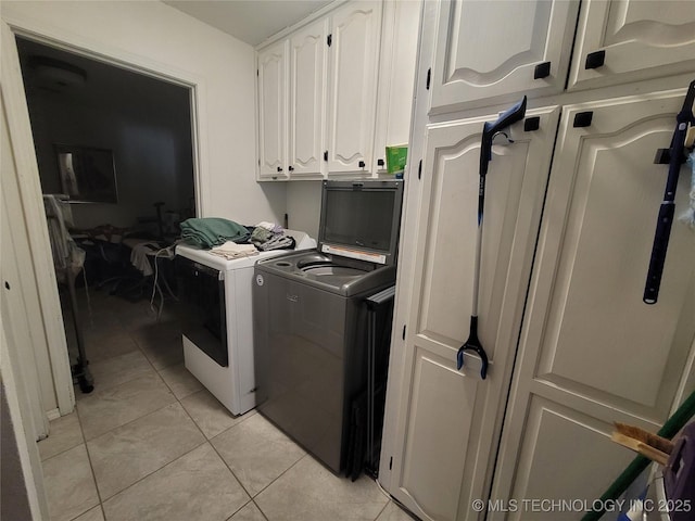 clothes washing area featuring light tile patterned floors, cabinet space, and washer and clothes dryer