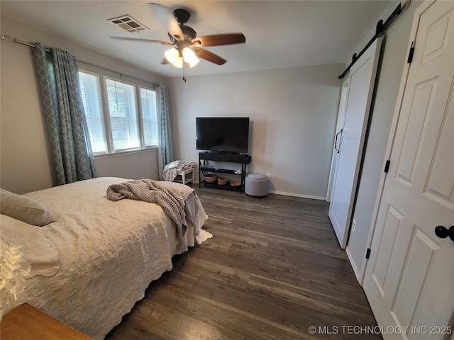 bedroom with visible vents, baseboards, a barn door, a ceiling fan, and dark wood-style flooring