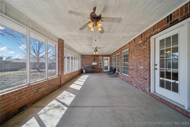 unfurnished sunroom with ceiling fan