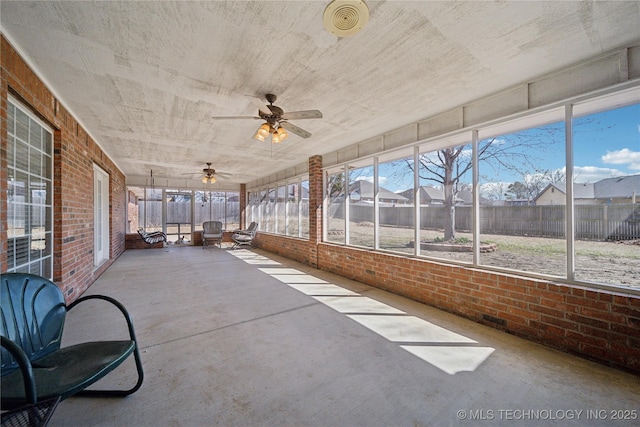 unfurnished sunroom with ceiling fan