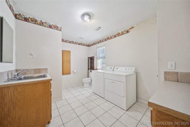 bathroom with visible vents, toilet, washer and clothes dryer, a sink, and tile patterned flooring