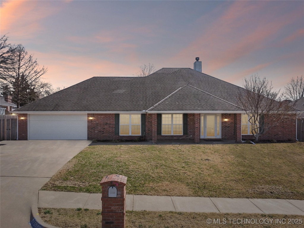 ranch-style home with an attached garage, a yard, brick siding, and driveway