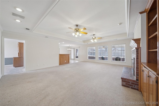 unfurnished living room featuring a tray ceiling, visible vents, a fireplace, and a ceiling fan