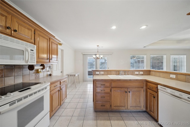 kitchen with white appliances, a sink, decorative backsplash, light countertops, and a chandelier