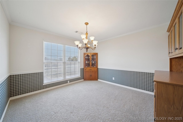 spare room with visible vents, ornamental molding, carpet flooring, wainscoting, and a notable chandelier