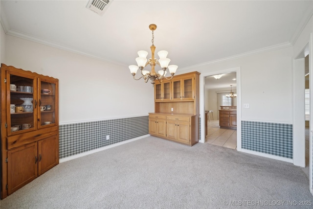 interior space featuring visible vents, wainscoting, crown molding, light carpet, and a notable chandelier