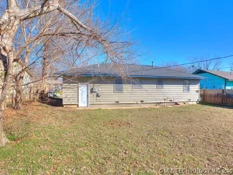 rear view of property featuring a lawn and fence