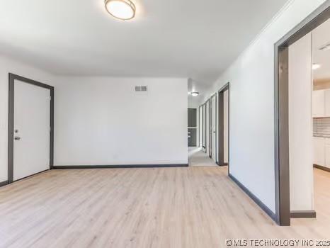 unfurnished room featuring visible vents, baseboards, and wood finished floors