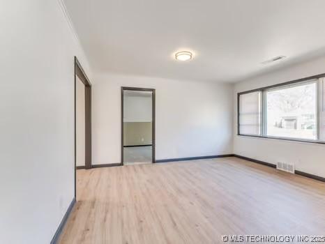 unfurnished room featuring visible vents, baseboards, and light wood finished floors