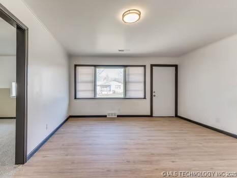 empty room featuring visible vents, baseboards, and wood finished floors