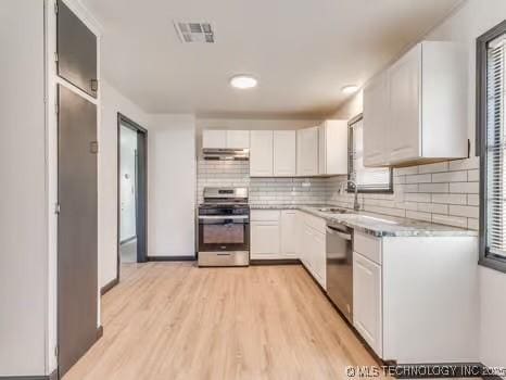 kitchen featuring visible vents, stainless steel appliances, light countertops, under cabinet range hood, and white cabinetry