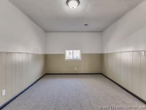 carpeted spare room featuring a wainscoted wall