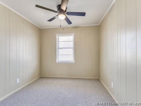 carpeted spare room with a ceiling fan and ornamental molding