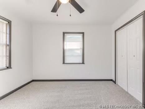 unfurnished bedroom with baseboards, multiple windows, and carpet flooring