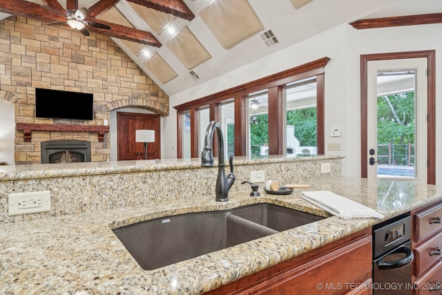 1721 E 136th Pl S, Bixby, OK 74008 - kitchen with ceiling fan, light stone counters, vaulted ceiling, a stone fireplace, and open floor plan
