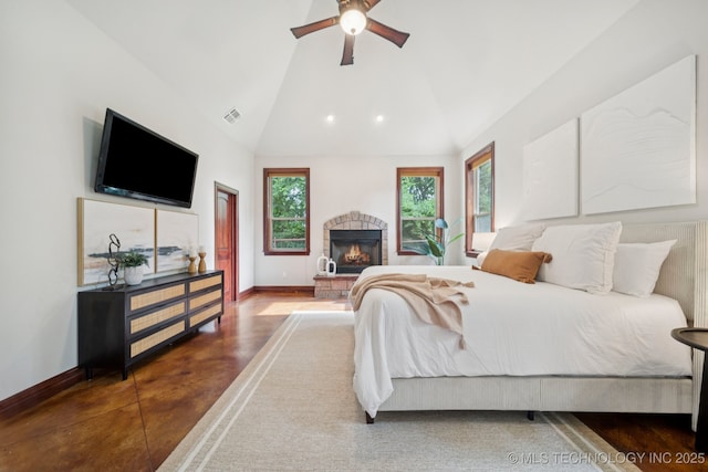 1721 E 136th Pl S, Bixby, OK 74008 - bedroom featuring concrete flooring, vaulted ceiling, a stone fireplace, and a ceiling fan