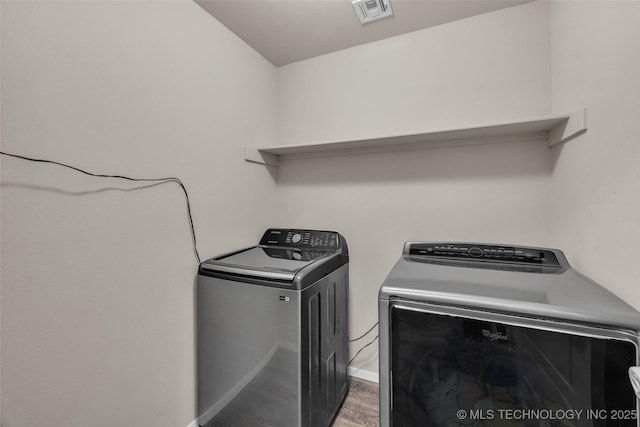 clothes washing area with visible vents, baseboards, laundry area, wood finished floors, and independent washer and dryer