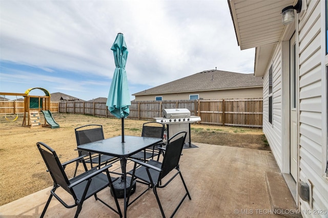 view of patio / terrace featuring grilling area, a playground, outdoor dining area, and a fenced backyard