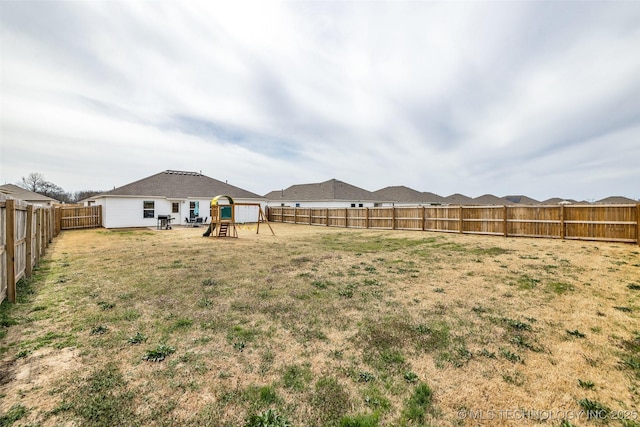 view of yard with a fenced backyard and a playground