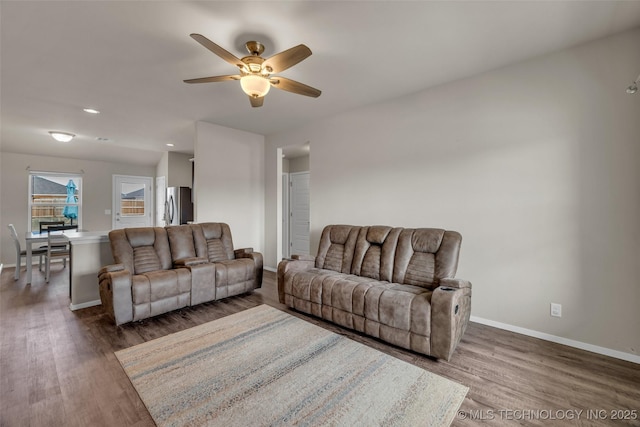 living room with baseboards, wood finished floors, and a ceiling fan