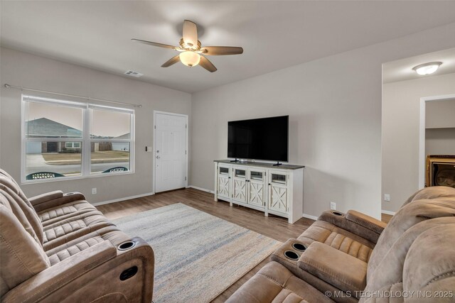 living area featuring visible vents, baseboards, wood finished floors, and a ceiling fan