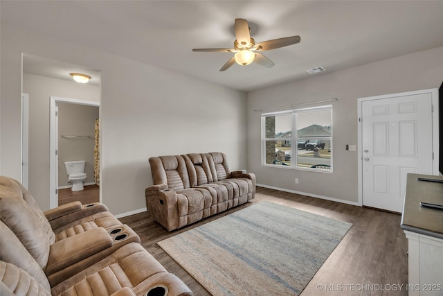 living area with visible vents, baseboards, wood finished floors, and a ceiling fan