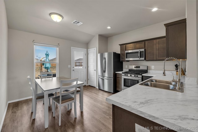 kitchen featuring visible vents, light wood-style flooring, a sink, stainless steel appliances, and dark brown cabinetry