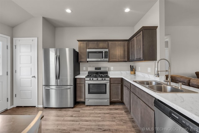 kitchen featuring dark brown cabinetry, recessed lighting, light wood-style flooring, appliances with stainless steel finishes, and a sink