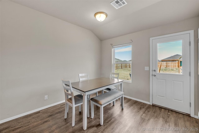 dining space with visible vents, lofted ceiling, baseboards, and wood finished floors