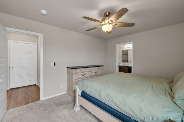 bedroom with connected bathroom, baseboards, light carpet, a ceiling fan, and a sink