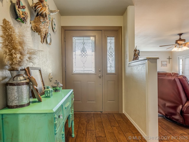 entryway with a textured wall, baseboards, a ceiling fan, and wood finished floors