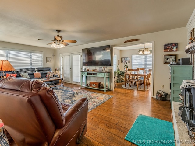 living room featuring ceiling fan with notable chandelier and hardwood / wood-style flooring