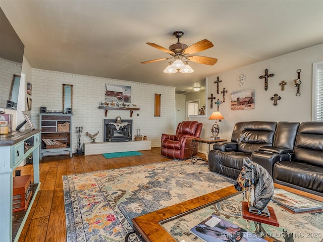 living area featuring dark wood finished floors, brick wall, and ceiling fan