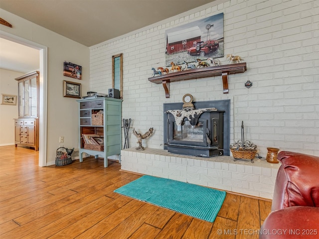 living area featuring baseboards, brick wall, wood finished floors, and a fireplace