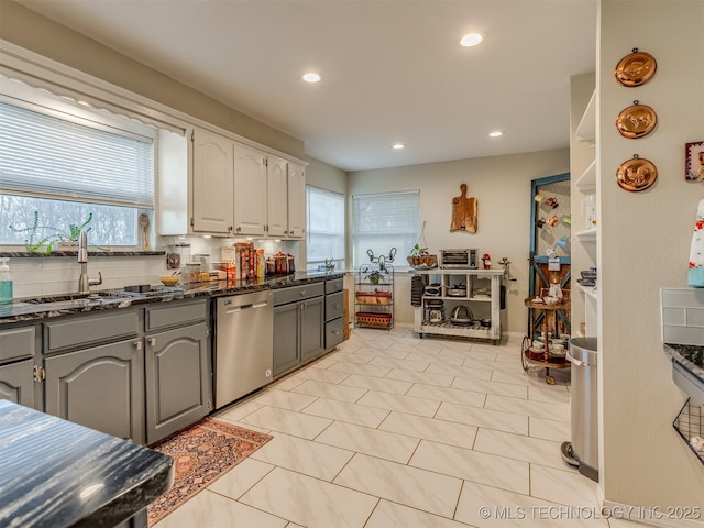 kitchen with a sink, dark stone countertops, white cabinetry, decorative backsplash, and dishwasher