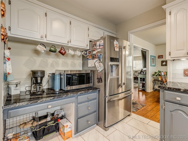 kitchen featuring white cabinetry, dark stone counters, tasteful backsplash, and appliances with stainless steel finishes