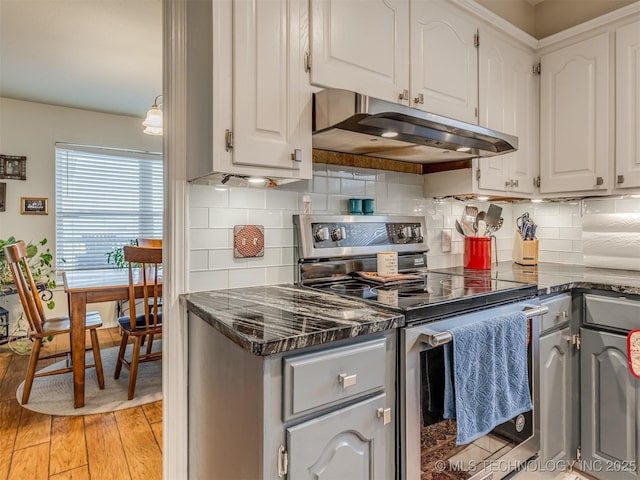 kitchen featuring under cabinet range hood, stainless steel electric range oven, light wood-type flooring, and white cabinets