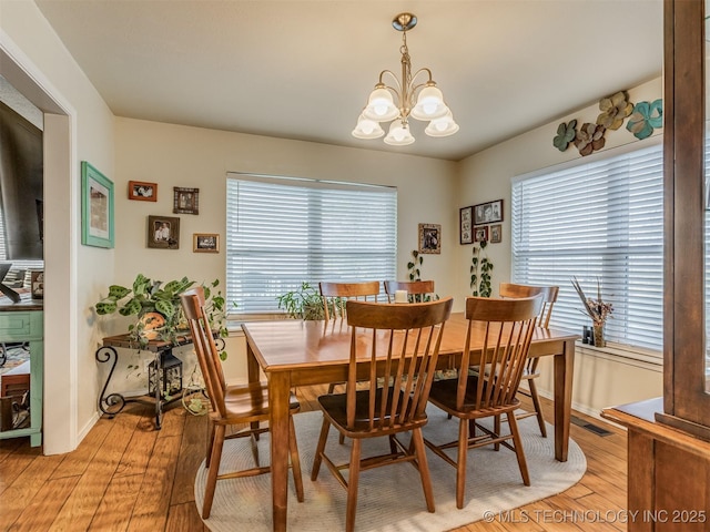 dining space featuring light wood-style flooring, baseboards, and a chandelier