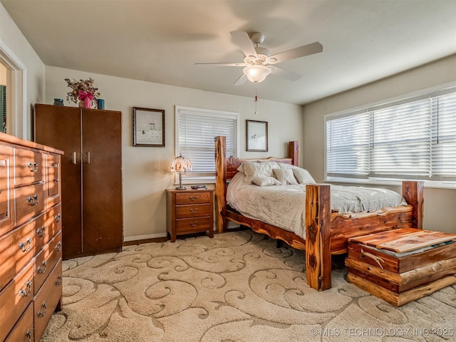 bedroom featuring baseboards, light colored carpet, and a ceiling fan