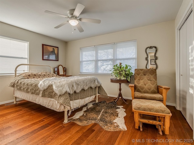 bedroom featuring a closet, ceiling fan, baseboards, and wood finished floors