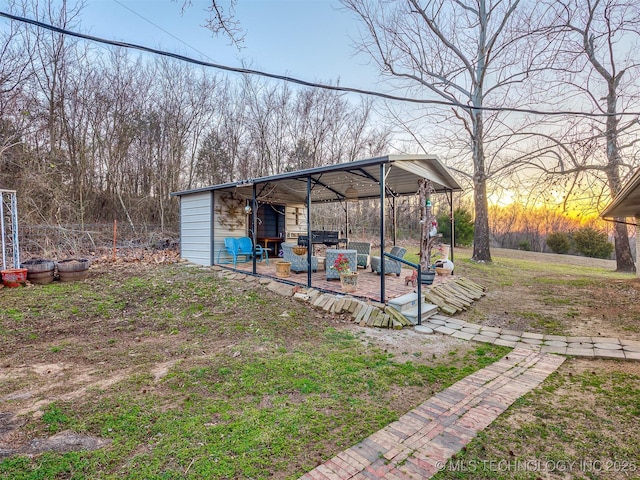 yard at dusk featuring an outbuilding and a carport