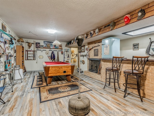 playroom featuring pool table, a bar, a textured ceiling, and wood finished floors